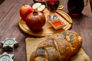 Hala, honey, apple and grenade and wine on the table with menorah and burning candles in honor of...