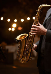 Musician is playing a saxophone on a stage with bokeh lights in the background