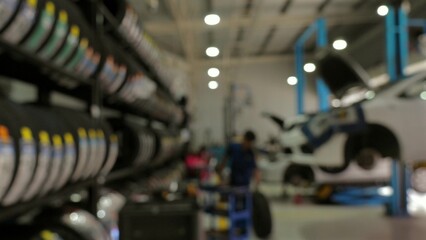 Blurred image of modern auto repair workshop with cars on lifts and tire racks, symbolizing automotive maintenance and repair.