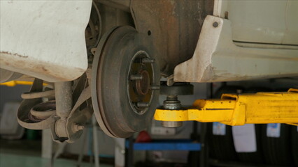 Close-up of car suspension system repaired in auto shop, fixing car wheel, automotive maintenance and mechanical engineering. Car Repair and Maintenance