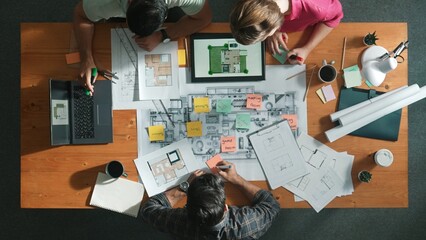 Top down view of civil engineer handed document while looking at blueprint. Aerial view of architect team brainstorming idea and planning building design while sitting at table with plan. Symposium.