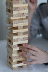 Board games; close-up of a hand building a tower of wooden blocks