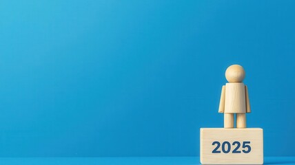 Wooden figure standing on a block labeled 2025 against a blue background.