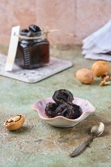 Green walnut jam in a pink bowl on a green concrete background. Exotic sweets, recipes from around the world.