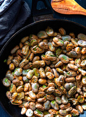 Broad beans stewed with onion and spices in a pan