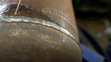 Welder applying water to cool down metal pipe.