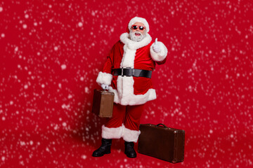 Photo of funny tourist old man prepare journey approve thumb up wear santa hat costume isolated red color background