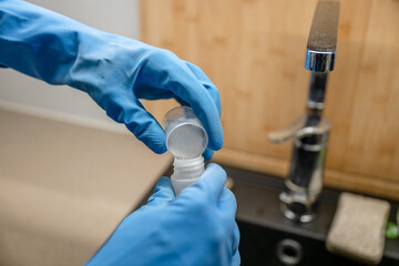 Close-up of a man's hand in a blue gloves mixing a detergent for cleaning the house