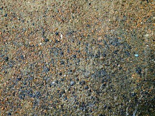 Multicolored asphalt texture with mixed stone granules, featuring earthy tones of brown, red, and black. Ideal for backgrounds, urban design, and construction projects.