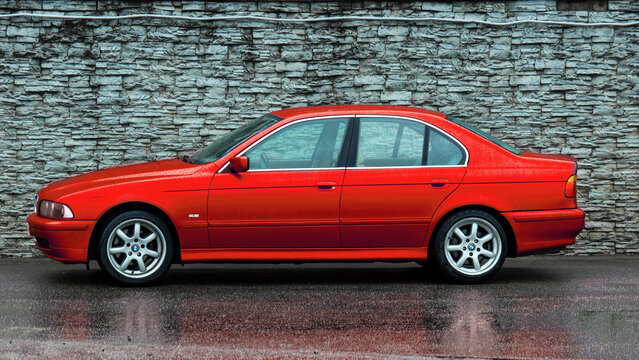 Side view of red BMW e39 sedan in rainy weather. Saint-Petersburg, Russia, 04.05.2021