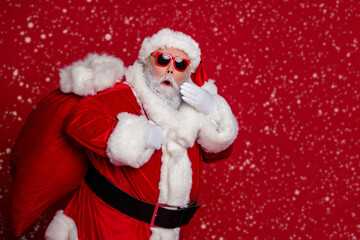 Photo of excited crazy retired man carry big bag gifts wow reaction wear santa hat costume isolated red color background
