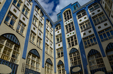 beige and blue facade of the house and blue sky and clouds above it. Hackesche Hoefe is a notable courtyard complex located adjacent to Hackescher Markt in the center of Berlin. 