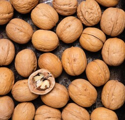 Close-up of walnuts in shells, poured on the surface in a layer. Harvest of nuts.