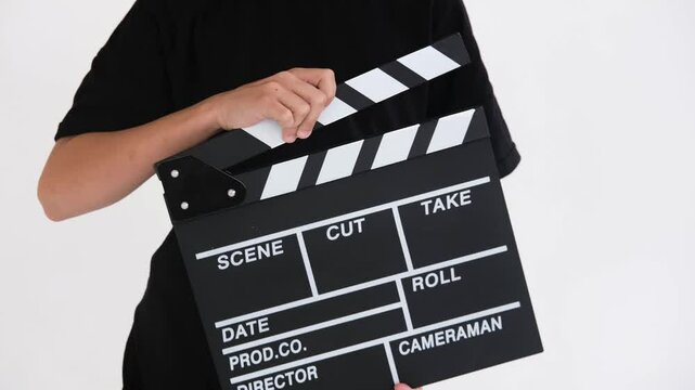 Child claps a movie slate in slow motion against a clean white background