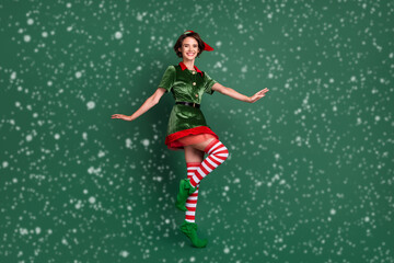 Photo of carefree funky lady dance stand tiptoe wear elf costume hat high socks isolated green color background