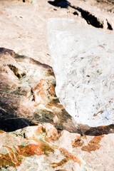 Piece of ice melting on a rock and sun reflecting on it