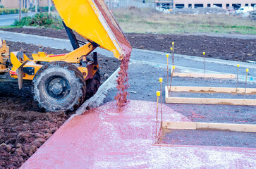 Construction workers laying fresh concrete pavement on a building site during daylight hours