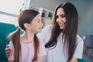 Photo of cute daughter speaking with mom embracing enjoying time together indoors apartment room