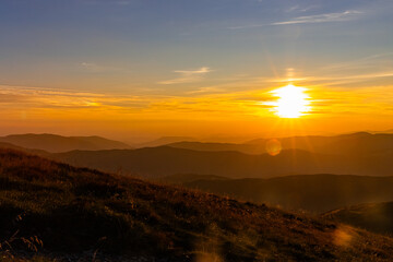 the sun sets over the mountains, casting golden light on everything