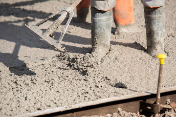 Skilled workers pouring concrete for strong foundation in  urban construction site on sunny day