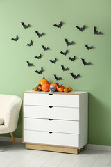 Chest of drawers with Halloween pumpkins, skull and paper bats in living room