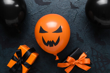 Different funny Halloween balloons with gift boxes and paper bats on dark background