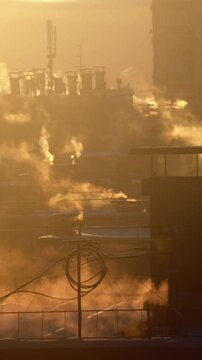 A chilly winter morning dawns, with the sun rising over the rooftops of tall buildings in Russia. The warm air rises from the vents of central heating systems