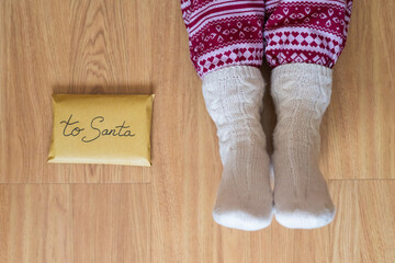 Cozy Socks and Christmas Pajama on a Wooden Floor, with a Letter Addressed to Santa.