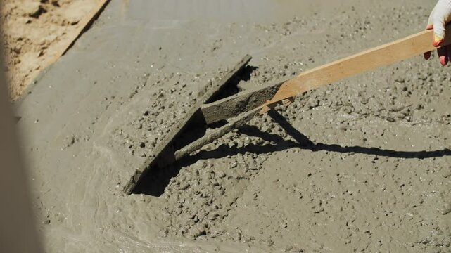 Builder leveling liquid concrete at the construction site