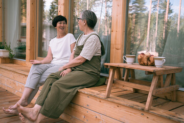 Two sisters senior women during conversation on wooden patio