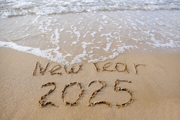 The inscription 2025 on the sand by the sea. Happy New Year.