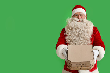 Santa Claus with pizza boxes on green background