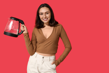 Beautiful young woman with modern electric kettle on red background