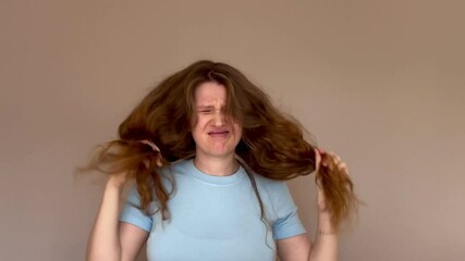 beautiful young long-haired woman shows her long, curly and red or light brown hair. concept don't like, sad, problem, split ends, hair quality