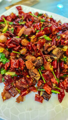 Close-up of a spicy Chinese dish. Red chili peppers, which are diced and stir-fried. Pieces of beef meat. Sichuanese dish. Intense spiciness  Regional specialty and food in Singapore, South East Asia