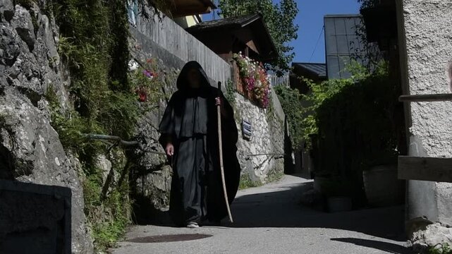 an elderly monk in a black cassock with a staff