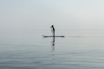 A girl at sea swims on a surfboard. Beautiful seascape