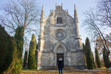 The girl looks at and takes pictures of a beautiful Catholic church against the background of incredible nature.