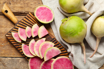 Board with cut ripe watermelon radishes on wooden background