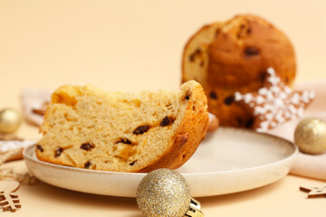 Plate with piece of Panettone and Christmas decor on beige background
