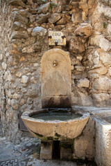 An old stone drinking fountain and bowl in the medieval village of Saint Paul de Vence in the south of France