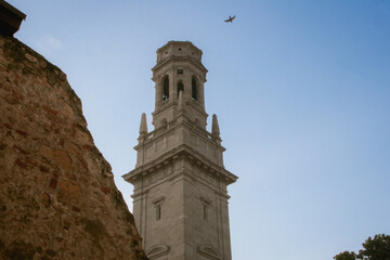 Fototapeta premium Campanile del Duomo di Verona tower around the corner and a ruin wall and with a bird in the sky. Verona, Italy
