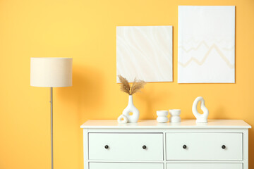 Lamp, pictures and white chest of drawers in interior of living room