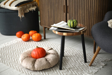 Coffee table with magazine and pumpkins in living room, closeup