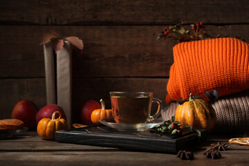 Composition with tray, cup of green tea and sweaters on wooden table near wall