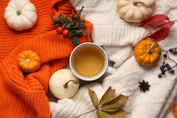 Autumn composition with cup of green tea, pumpkins and leaves on sweaters as background