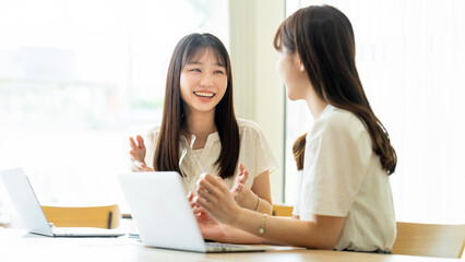 パソコンを使いながら話す2人の女性