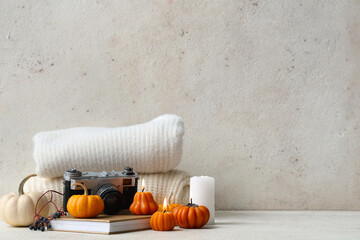 Burning candles with pumpkins, book, berries and photo camera on white background