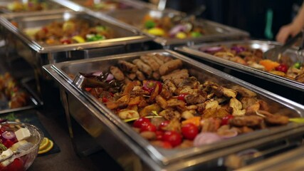 A vibrant buffet table displays an array of grilled meats and fresh vegetables, complemented by colorful garnishes and side dishes. Perfect for a community gathering.