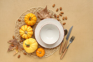 Beautiful table setting with fresh pumpkins, almond nuts and autumn leaves on brown background